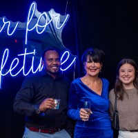 Boy and two girls and President Mantella stand in front of Laker for a Lifetime neon sign